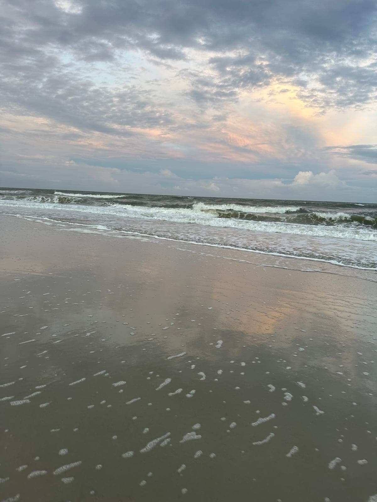 Evening clouds reflected on the wet sand at low tide